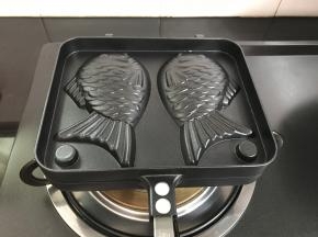 稠鱼烧模具放燃气灶上加热。