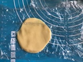 取一份菠萝皮面团，上下铺保鲜膜，擀开成面片状。