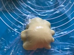 去掉下层的保鲜膜，将面片覆盖到面包面团上。