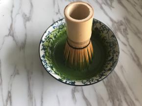 剩余50克牛奶隔水加热到60度，倒入抹茶粉中，用茶筅顺着一个方向打匀。