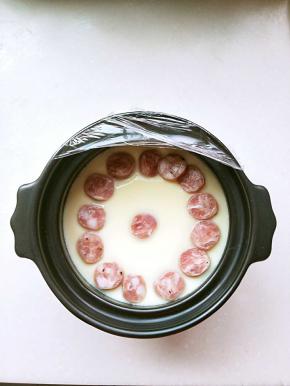 碗锅端起来有轻微晃动就行，放入切片的鲜肉肠。继续蒸4.5分钟。