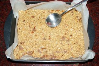 将混合物倒入垫有吸油纸的长方形烤盘中，抹平压实。