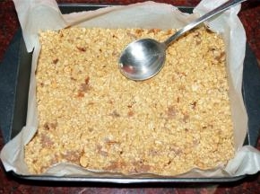 将混合物倒入垫有吸油纸的长方形烤盘中，抹平压实。