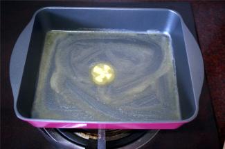 烤盘220度，上下火预热15分钟的同时，将烤盘放置入烤箱内。取出烤热了的烤盘，用黄油粒均匀涂抹烤盘底部。