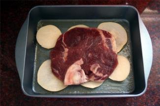 将雪梨片铺在烤盘底部，上面放上T骨牛排。