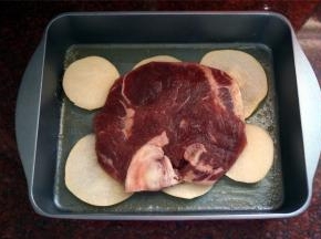 将雪梨片铺在烤盘底部，上面放上T骨牛排。