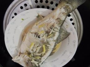 蒸好的鲈鱼取出，拣去葱姜