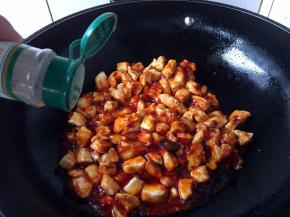 把鸡丁翻炒均匀，放入1小勺白胡椒粉，再翻炒两下。