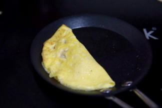 用筷子掀起一侧的蛋皮包过来，贴合在一起即可