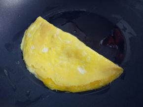 热锅热油，小火，将蛋液倒入，底部稍凝固后，掀起一半盖到另一半上