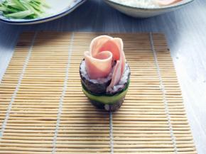 用刮刀将黄瓜顺向刮一个长条，在紫菜包饭底部围一圈固定