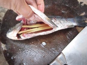 在鱼肚中放入姜片，抹上料酒和盐。腌渍15分钟。