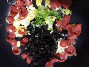 倒入木耳和葱花翻炒至木耳出现啪啪的响声，加盐调味