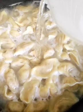 水再次沸腾后轻轻翻动水饺，点少许凉水，转中火继续煮至沸腾，再点水，如此四五次直到水饺煮熟