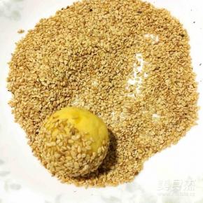 将丸子放入装有芝麻的盘子里滚一下，让表面滚上芝麻