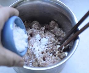 2、猪肉里加入准备好的白糖、胡椒粉、盐，用筷子顺一个方向不停的搅拌