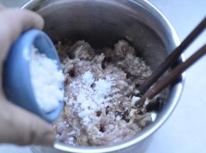 2、猪肉里加入准备好的白糖、胡椒粉、盐，用筷子顺一个方向不停的搅拌