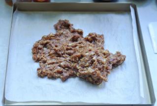 5、烤盘里脯上油纸，将腌好的猪肉泥放在上面，