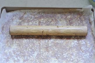 8、将擀好的肉上，刷一层蜂蜜水，撒上白芝麻，垫上油纸再用擀面杖压平，提前将烤箱预热