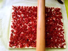 均匀的铺上蔓越梅，再用擀面杖轻轻擀几下，让蔓越梅黏在面片上，免得一会卷起来时脱落