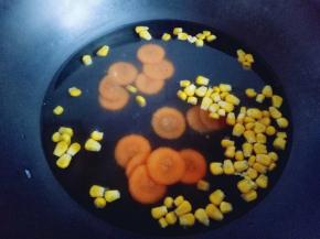 玉米粒和胡萝卜片焯水: 水烧开后倒入两种蔬菜，1分钟捞出，淋干水份。