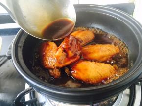 取一款耐高温砂锅，放入鸡翅和汤汁，大火煮开。