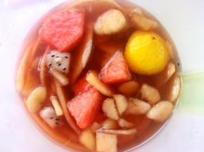 将煮好的玫瑰花果茶趁热倒入水果容器中，加入黄冰糖搅拌均匀