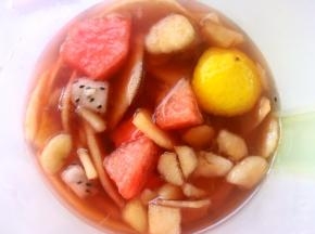 将煮好的玫瑰花果茶趁热倒入水果容器中，加入黄冰糖搅拌均匀