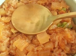 取一个圆形小碗，把米饭放进去，借助勺子压紧