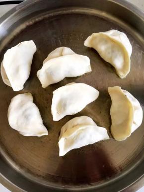 平底锅放油，端起锅侧着旋转一下，使整个锅底都沾上油，将包子摆在上面，中间间隔空隙