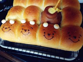 脱模晾凉的同时，用隔水融化的黑巧克力画出维尼熊的五官，另在头部挤少许巧克力，粘住用来做耳朵的旺仔小馒头。