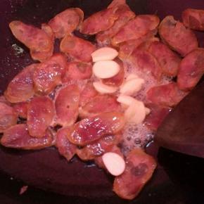 热锅凉油，下蒜子、腊肠煸出油脂。