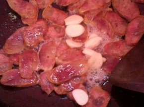 热锅凉油，下蒜子、腊肠煸出油脂。