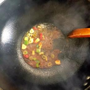 4、锅中倒入油烧热后加入葱、姜、蒜、辣椒爆香，加入黄酱炒匀