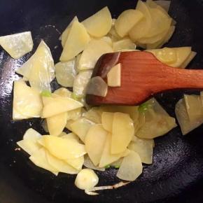 5、加少量水和生抽翻炒至土豆片断生