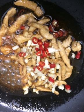 在将姜、蒜和小米椒倒入炒出蒜香味