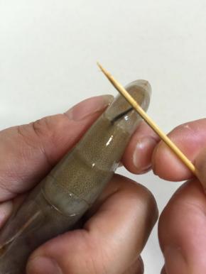将牙签对准虾背部，从头数第二个关节处，戳进去，挑住虾线。

