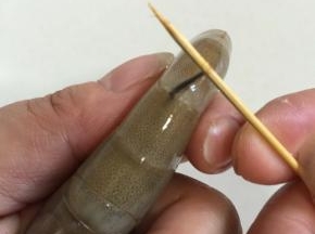 将牙签对准虾背部，从头数第二个关节处，戳进去，挑住虾线。
