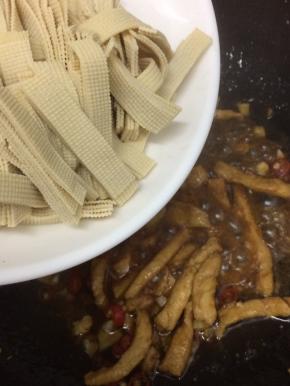 在将干豆腐条放入翻炒片刻