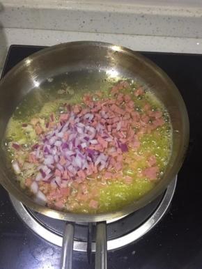 锅里加入黄油化开以后把切好的洋葱粒火腿粒，加入少量黑胡椒，盐炒香