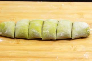 菠菜面皮卷起，把面团切成大小相同的等分，擀成包子皮；