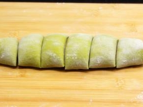 菠菜面皮卷起，把面团切成大小相同的等分，擀成包子皮；