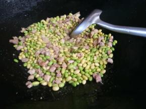 把焯好的毛豆放入与肉丁一起翻炒。