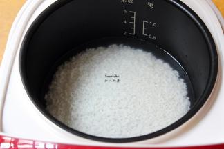 浸泡的米捞出，放入电饭锅，加入适量的清水，按煲饭键；