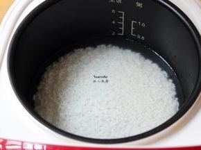 浸泡的米捞出，放入电饭锅，加入适量的清水，按煲饭键；