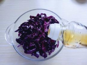 将腌好的紫甘蓝的水份挤干，加入芝麻油。