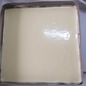 将拌匀的蛋糕糊从高处倒入垫好油纸的金盘中，用刮刀抹平，然后震动金盘，震出大气泡。