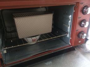 烤箱中放一碗热水，吐司盒开口放入烤箱中，开启发酵模式，进行第二次发酵