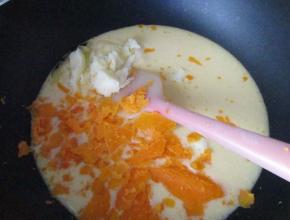 把拌好的糊倒入不粘锅中，放入黄油和压碎的咸蛋黄搅拌均匀