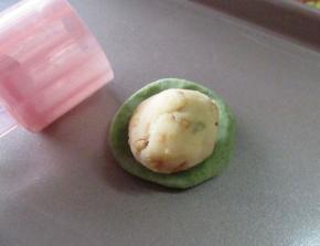 然后用绿色皮包裹馅料包严实放入模具中